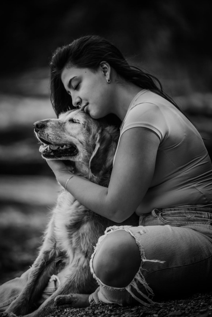 Black and white photo of a woman embracing her dog in a loving hug.