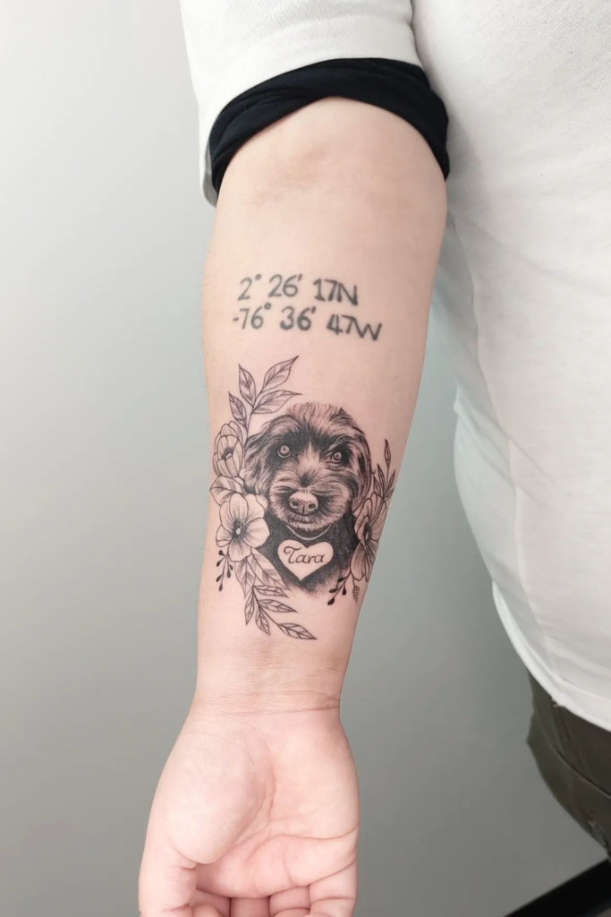 Arm tattoo memorializing a dog, with its portrait framed by flowers and a significant location's coordinates.