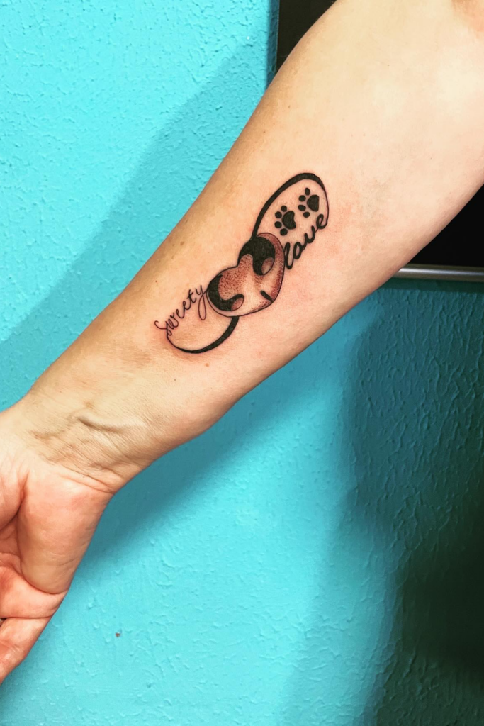 Arm tattoo of a dog's nose, paws, and the word 'love' in a realistic style