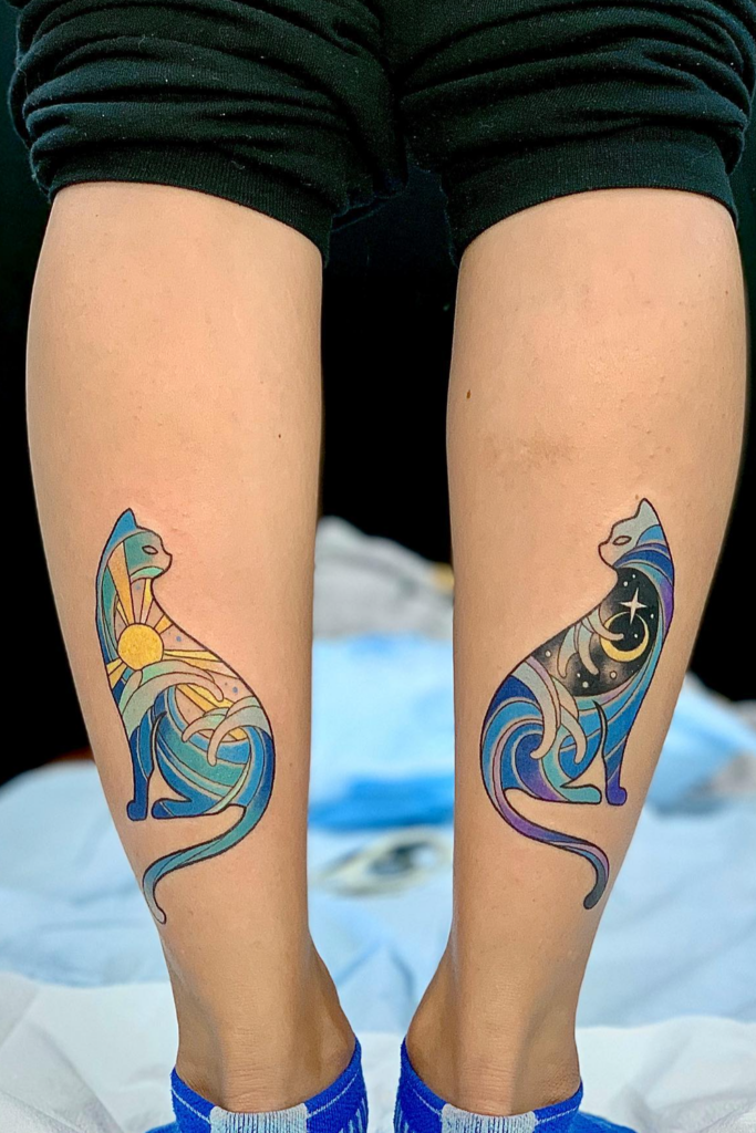 Mirrored cat tattoos on both legs, depicting the cats in a playful, head-bent pose