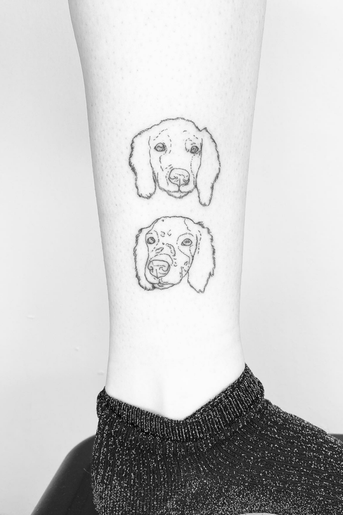 Tattoos of two dog faces on a person's leg