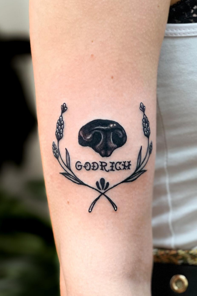 Tattoo of a dog's nose on a person's upper leg, with the name 'Godrich' below.