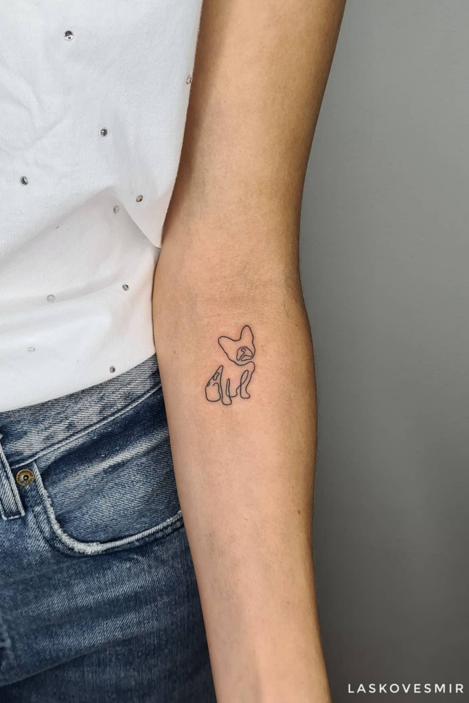 Simple, minimalist dog tattoo on a woman's left forearm