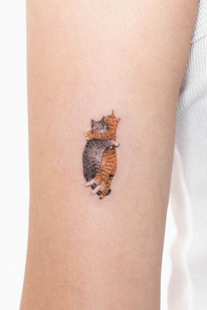 Leg tattoo showcasing the affectionate bond between two cats in a realistic style.